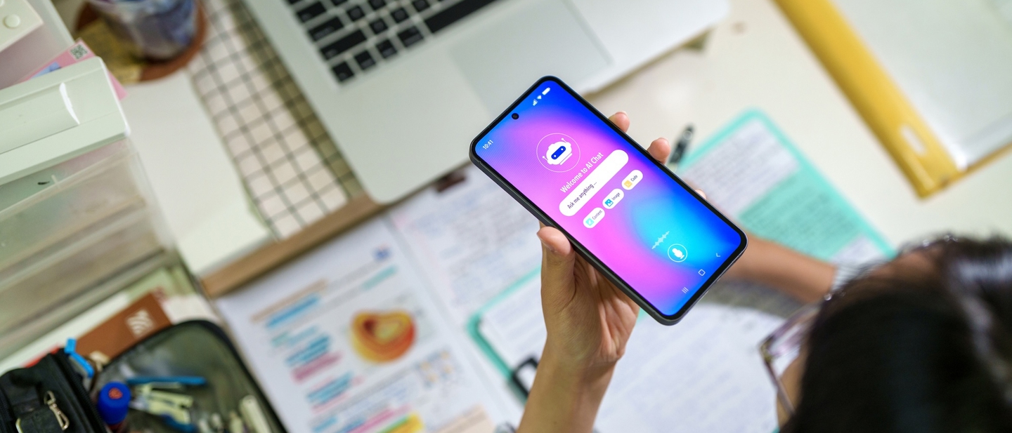 A person at a desk using their phone to do a voice AI search